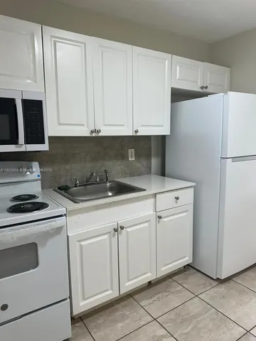a kitchen with white cabinets and white appliances