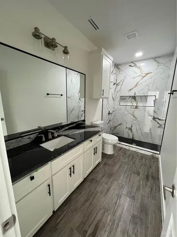 a large white bathroom with a granite countertop sink toilet and shower