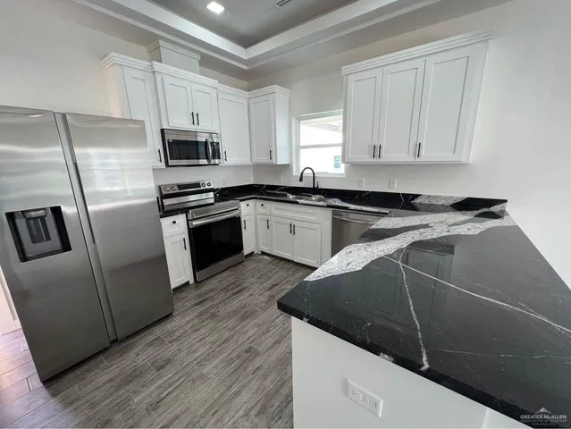 a kitchen with granite countertop a sink a counter space stainless steel appliances and cabinets