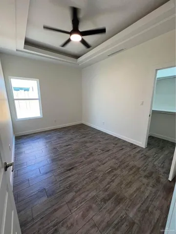 an empty room with wooden floor fan and windows