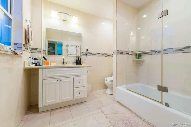 a bathroom with a double vanity sink a toilet mirror and bathtub
