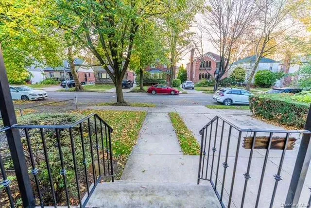 a view of street with small yard and large trees