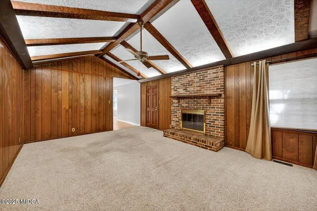 a view of an empty room with a fireplace and windows