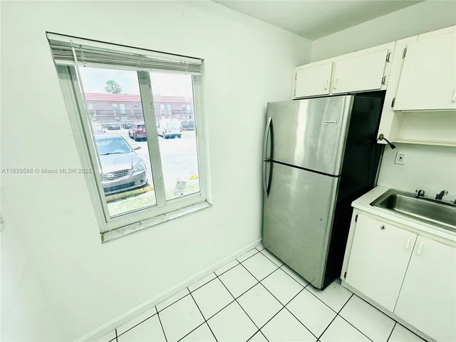 a utility room with wooden floor and a refrigerator