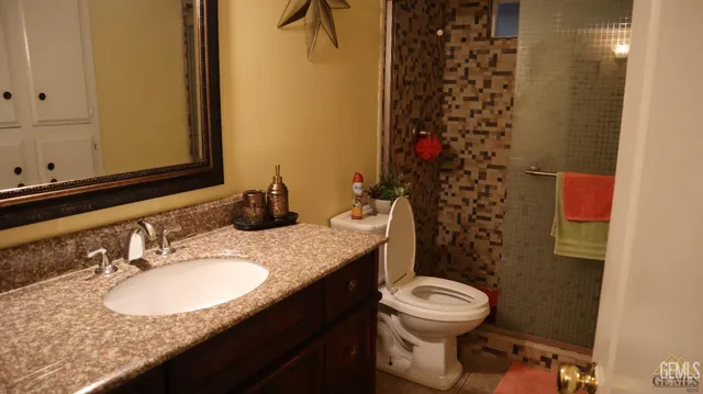 a bathroom with a granite countertop toilet sink mirror and vanity