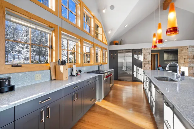 a large kitchen with stainless steel appliances granite countertop a large window and a sink