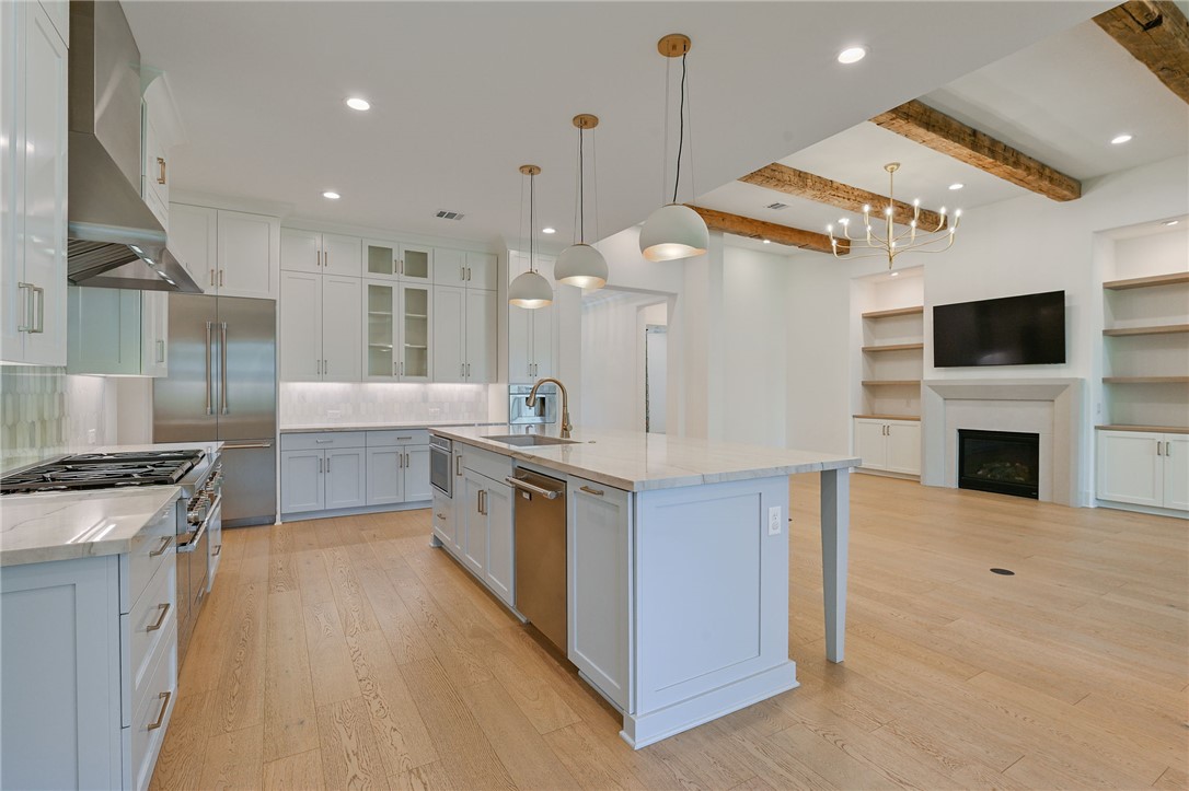 5115 Inverness Drive Bryan, TX 77802 - Photo 8 of 28 Kitchen featuring a large central island with a light blue finish, light wood-finish flooring, white upper cabinetry, light blue lower cabinetry, and stainless steel appliances