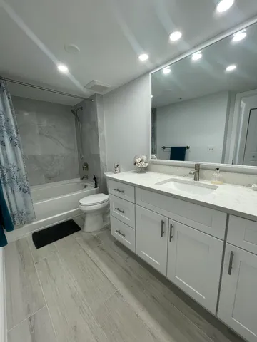 a bathroom with a sink a toilet a mirror and shower