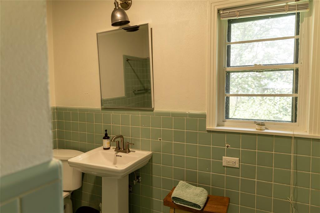 3228 Colcord Avenue Waco, TX 76707 - Photo 16 of 29 Bathroom featuring a pedestal sink with a brushed nickel faucet, a rectangular mirror, and a wall-mounted light fixture