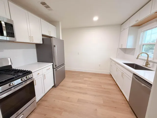 a kitchen with granite countertop a sink a stove and refrigerator