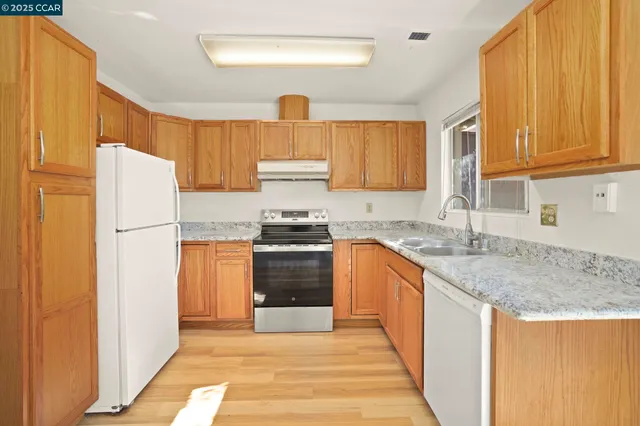 a kitchen with granite countertop a refrigerator stove top oven and sink