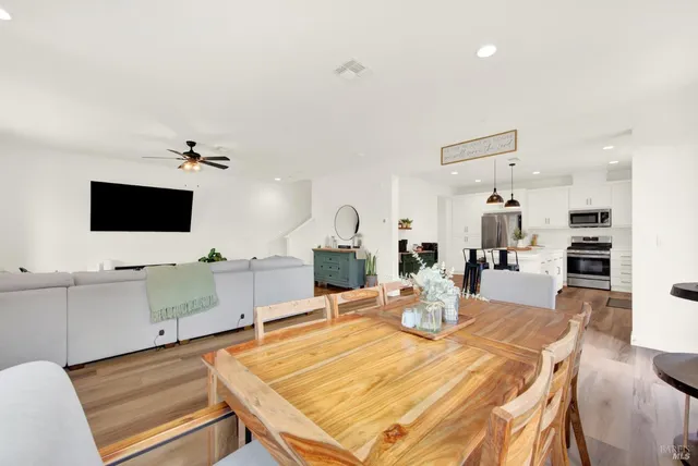 a kitchen with stainless steel appliances granite countertop a sink a stove a refrigerator and chairs with wooden floor