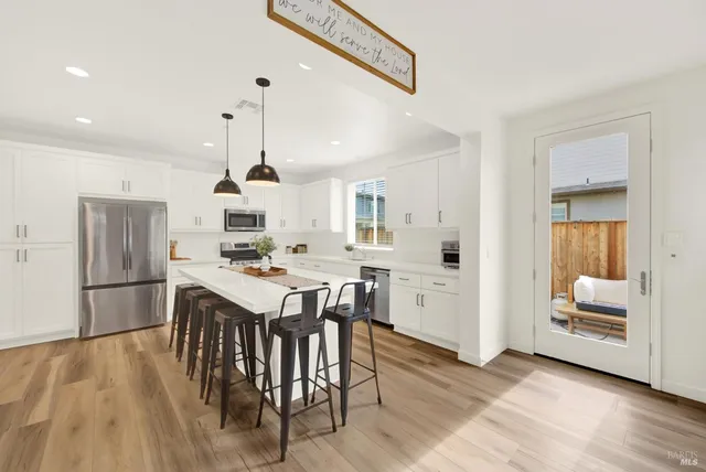 a open kitchen with stainless steel appliances granite countertop a stove and a wooden floors
