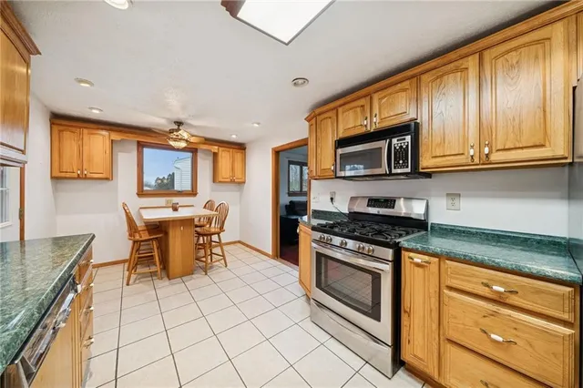 a kitchen with stainless steel appliances granite countertop a stove top oven a sink dishwasher a dining table and chairs with wooden floor