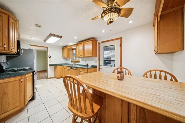 a kitchen with stainless steel appliances granite countertop a sink a stove a dining table and chairs with wooden floor