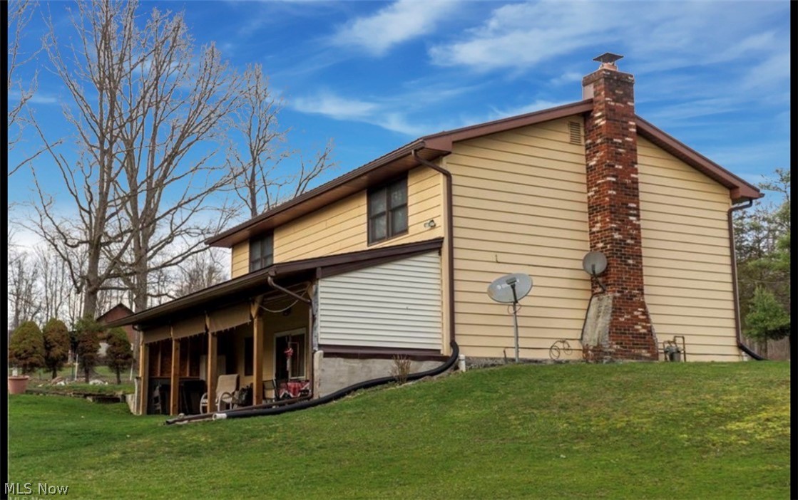 871 South County Line Road Geneva, OH 44041 - Photo 3 of 20 View of side of home featuring a lawn and a chimney