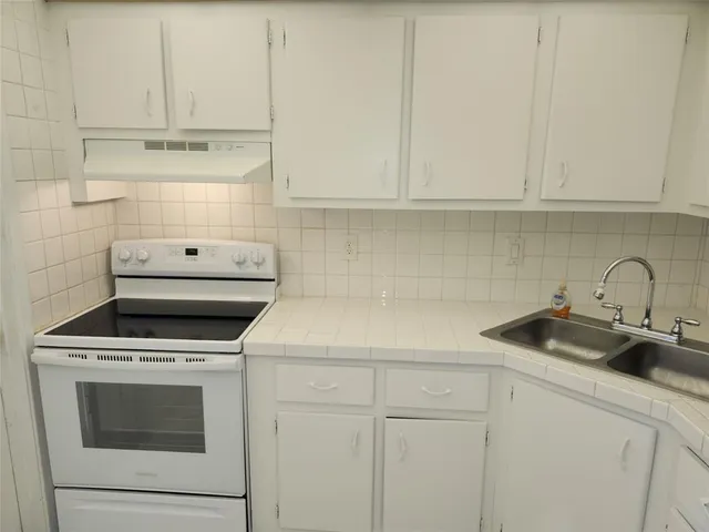a kitchen with white cabinets and appliances