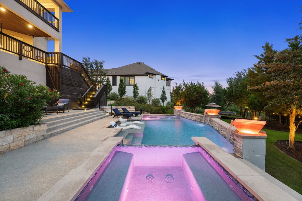 215 Lodestone Lane Austin, TX 78738 - Photo 38 of 40 A lavish backyard oasis with a sparkling pool and spa, featuring elegant tiered landscaping and inviting outdoor lighting.