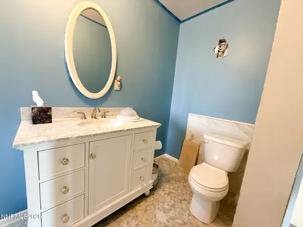 a bathroom with a granite countertop toilet a sink and a mirror