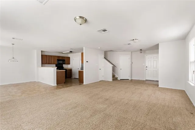 an empty room with kitchen and natural light