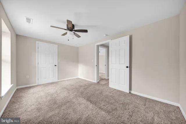 an empty room with closet and ceiling fan