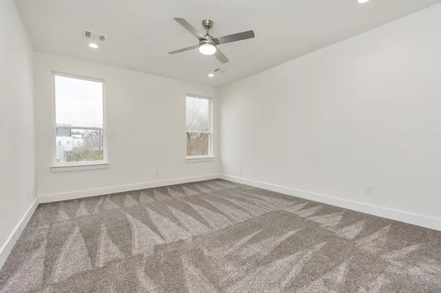 an empty room with windows and ceiling fan