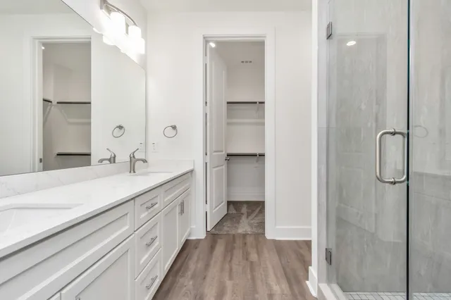 a spacious bathroom with a double vanity sink a mirror and shower