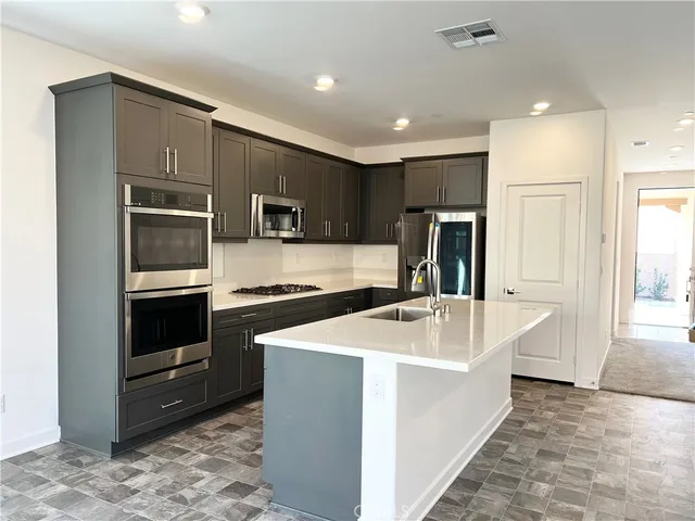 a kitchen with stainless steel appliances a sink a stove a microwave and wooden cabinets