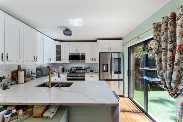 a kitchen with stainless steel appliances granite countertop a refrigerator a stove and a sink with wooden floor