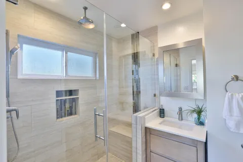 a bathroom with a sink vanity granite tub shower and a mirror