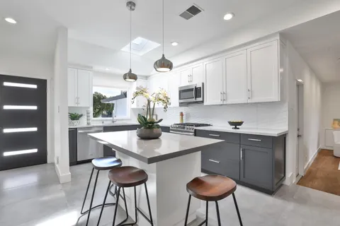 a kitchen with stainless steel appliances a dining table chairs sink and cabinets