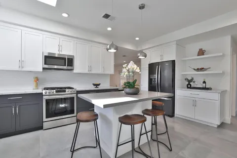 a kitchen with stainless steel appliances a stove a sink a refrigerator and white cabinets