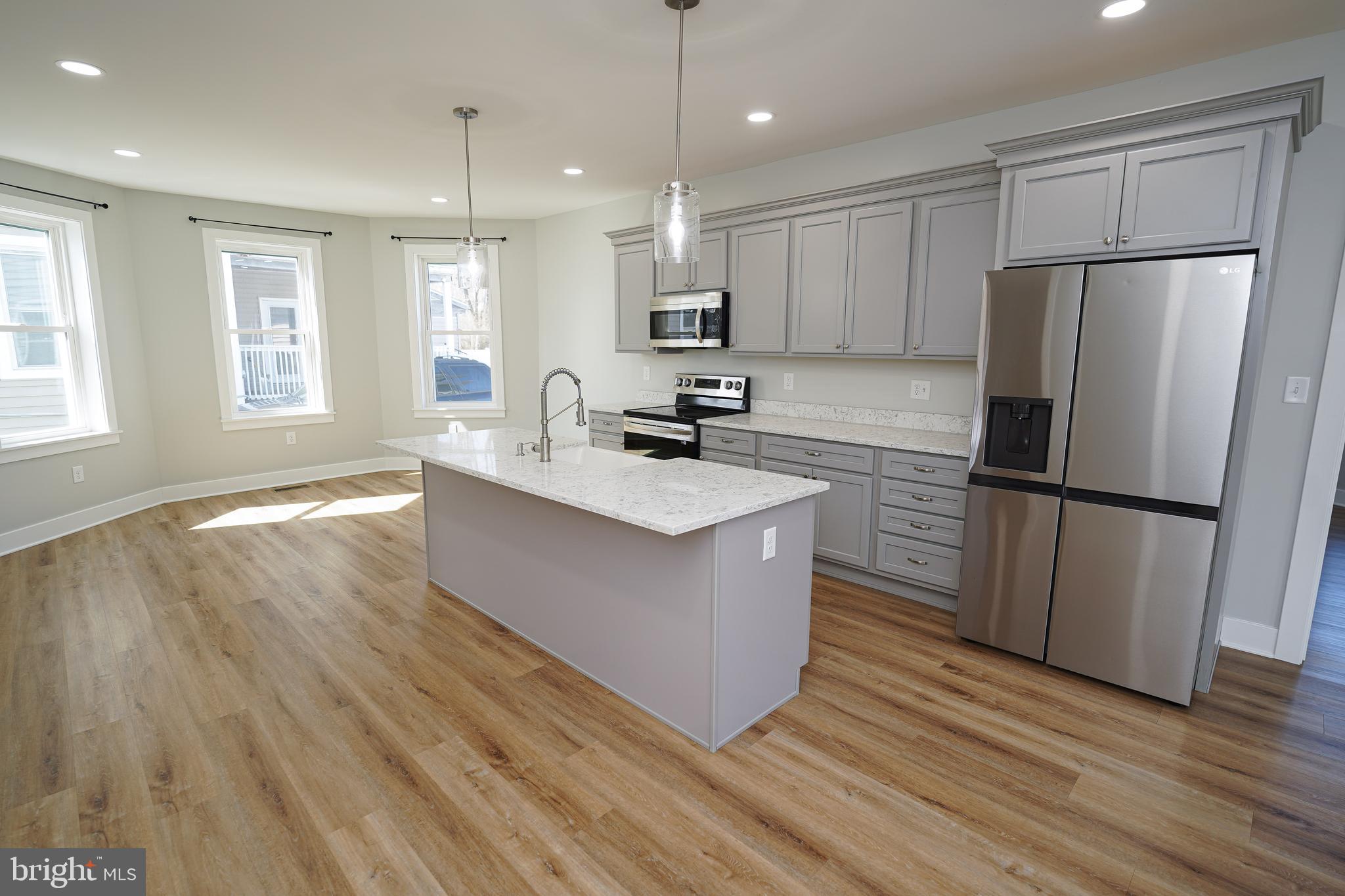 111 East Jewell Street Delmar, DE 19940 - Photo 15 of 59 a kitchen with wooden floors white cabinets and stainless steel appliances