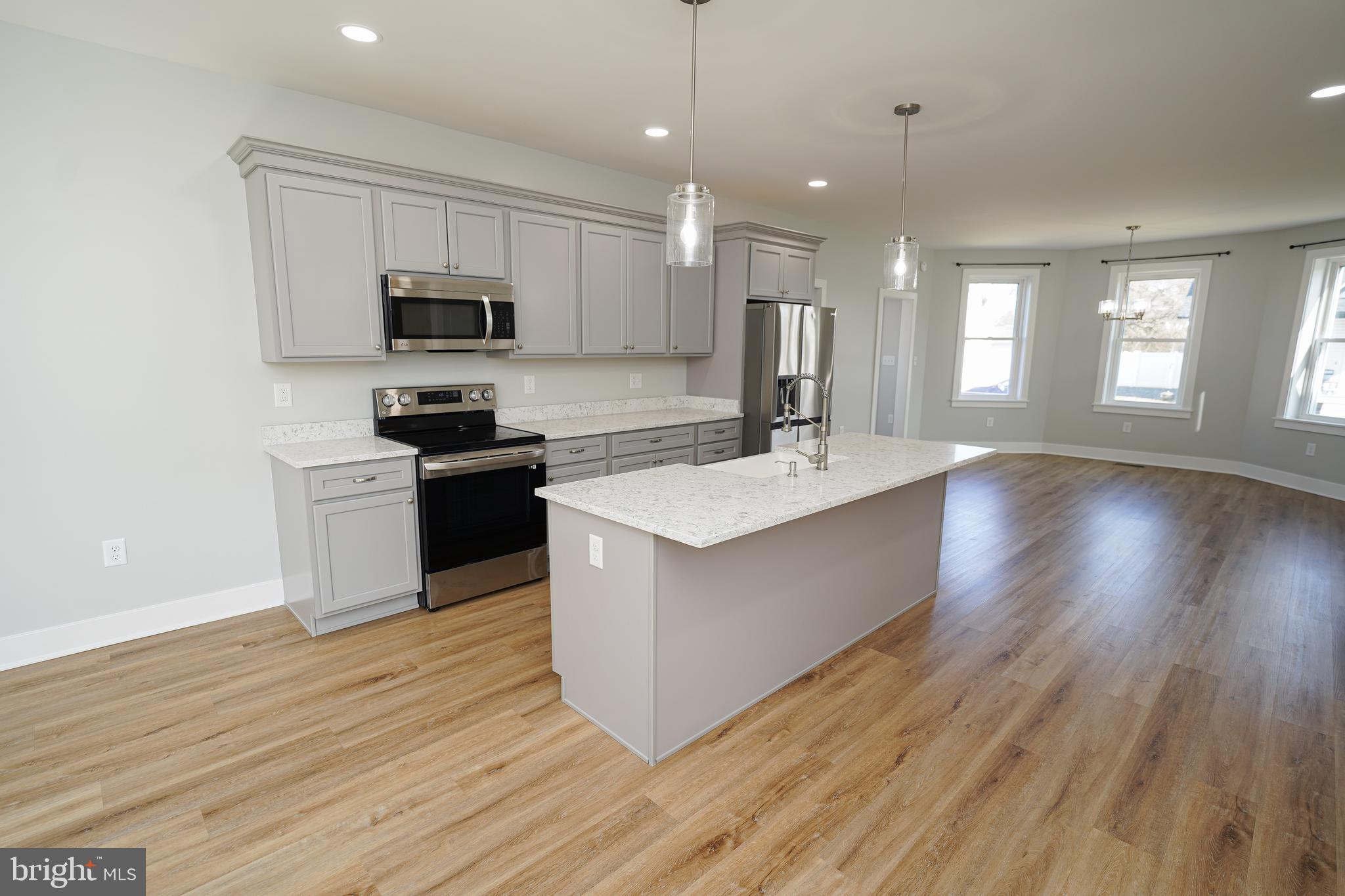 111 East Jewell Street Delmar, DE 19940 - Photo 16 of 59 a large white kitchen with kitchen island a sink wooden floor and stainless steel appliances
