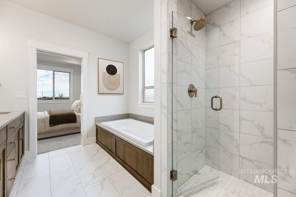3281 East Englehart Lane Meridian, ID 83642 - Photo 12 of 35 Ensuite bathroom featuring a shower stall, vanity, a garden tub, and light marble finish flooring