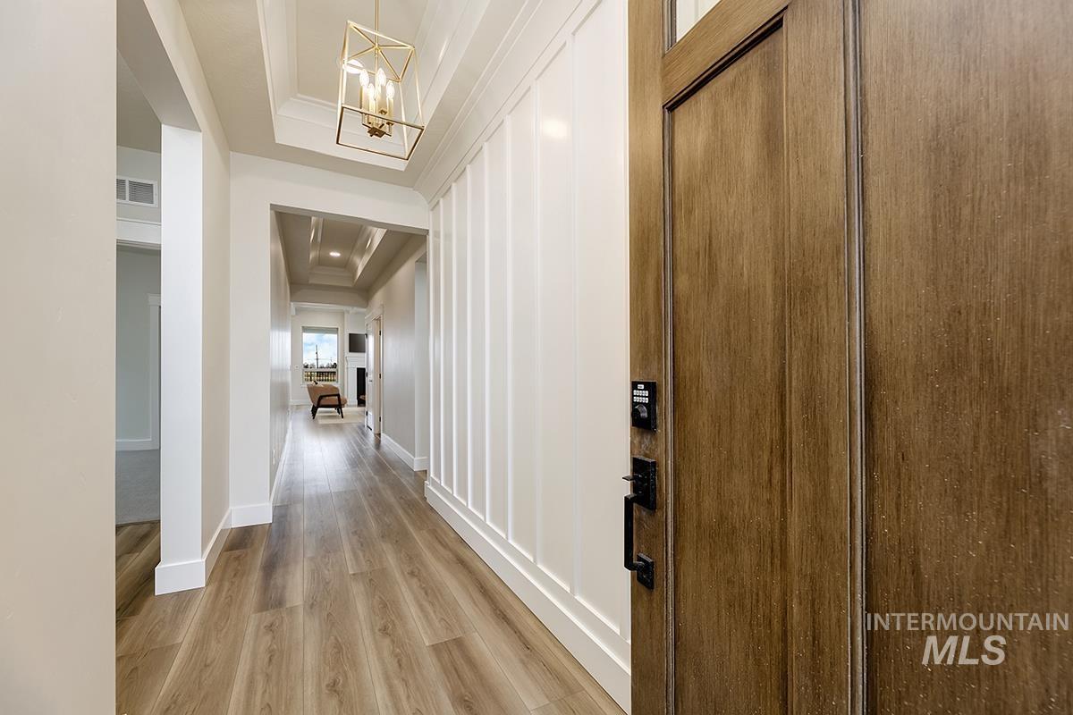 3281 East Englehart Lane Meridian, ID 83642 - Photo 2 of 35 Hallway with a tray ceiling, light wood-style flooring, and hanging lights