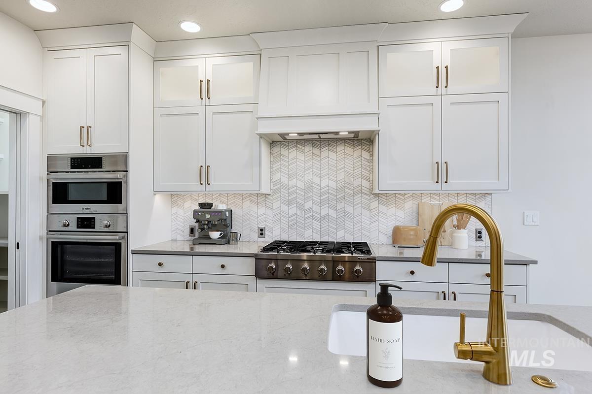 3281 East Englehart Lane Meridian, ID 83642 - Photo 6 of 35 Kitchen featuring white cabinets, light stone countertops, backsplash, and recessed lighting