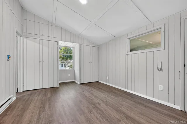 an empty room with wooden floor closet and windows