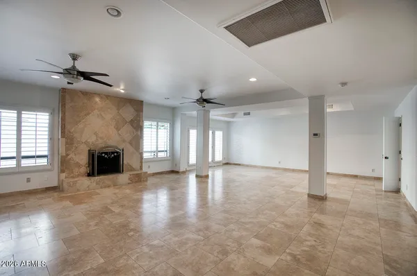 an empty room with windows and fireplace