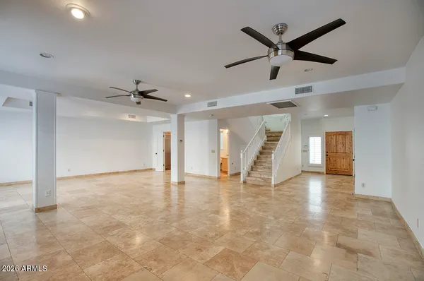 an empty room with ceiling fan and windows