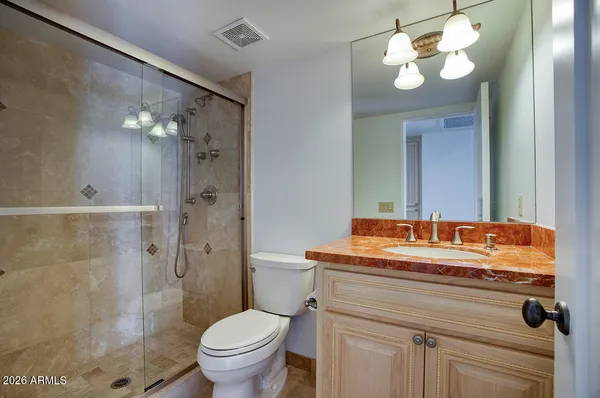 a bathroom with a granite countertop sink a toilet and a mirror