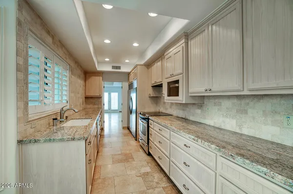 a large kitchen with granite countertop a large counter top space appliances and cabinets