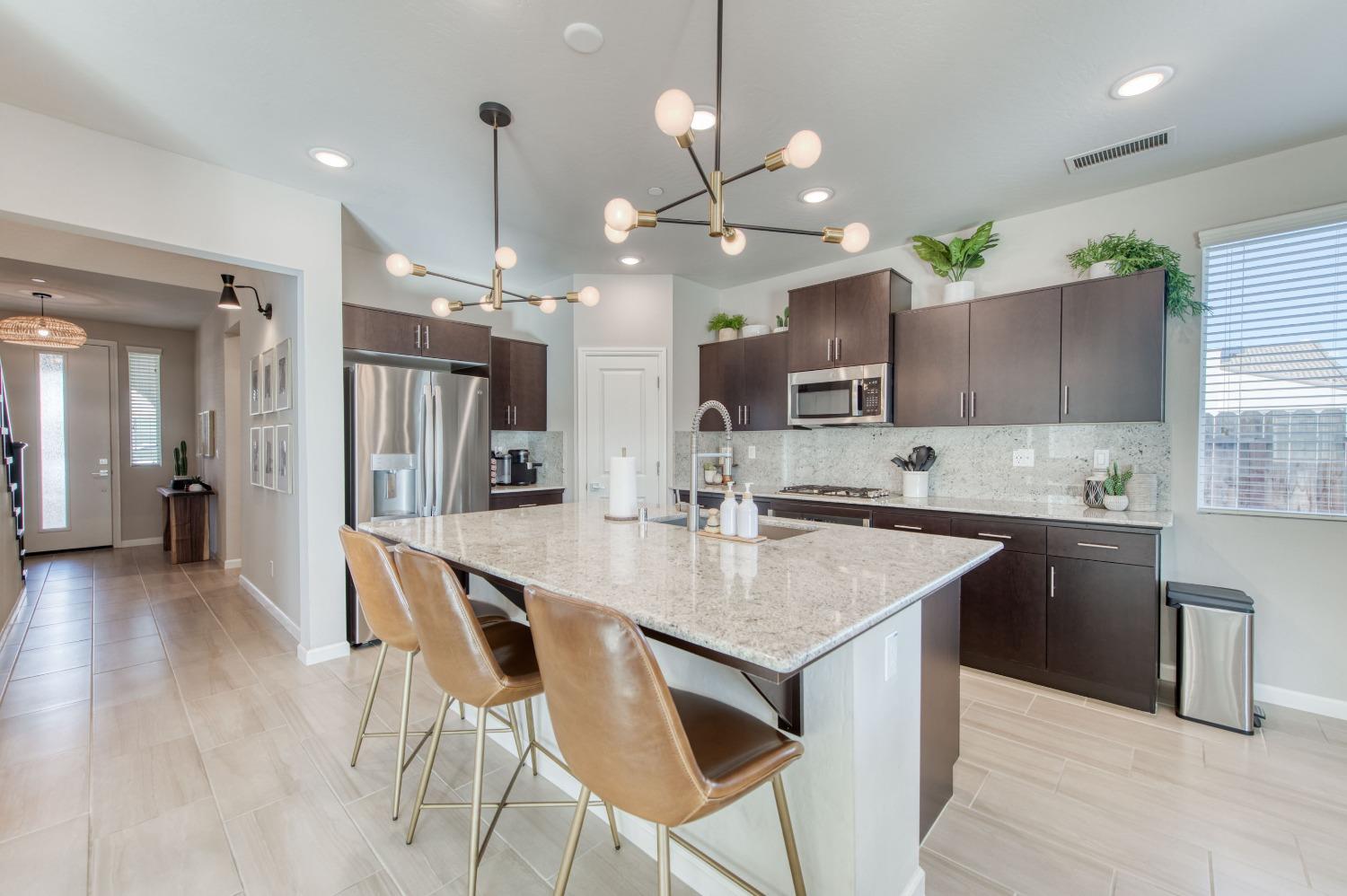 4136 Mecca Avenue Clovis, CA 93619 - Photo 19 of 44 a kitchen with stainless steel appliances granite countertop a kitchen island a stove a table and chairs in it