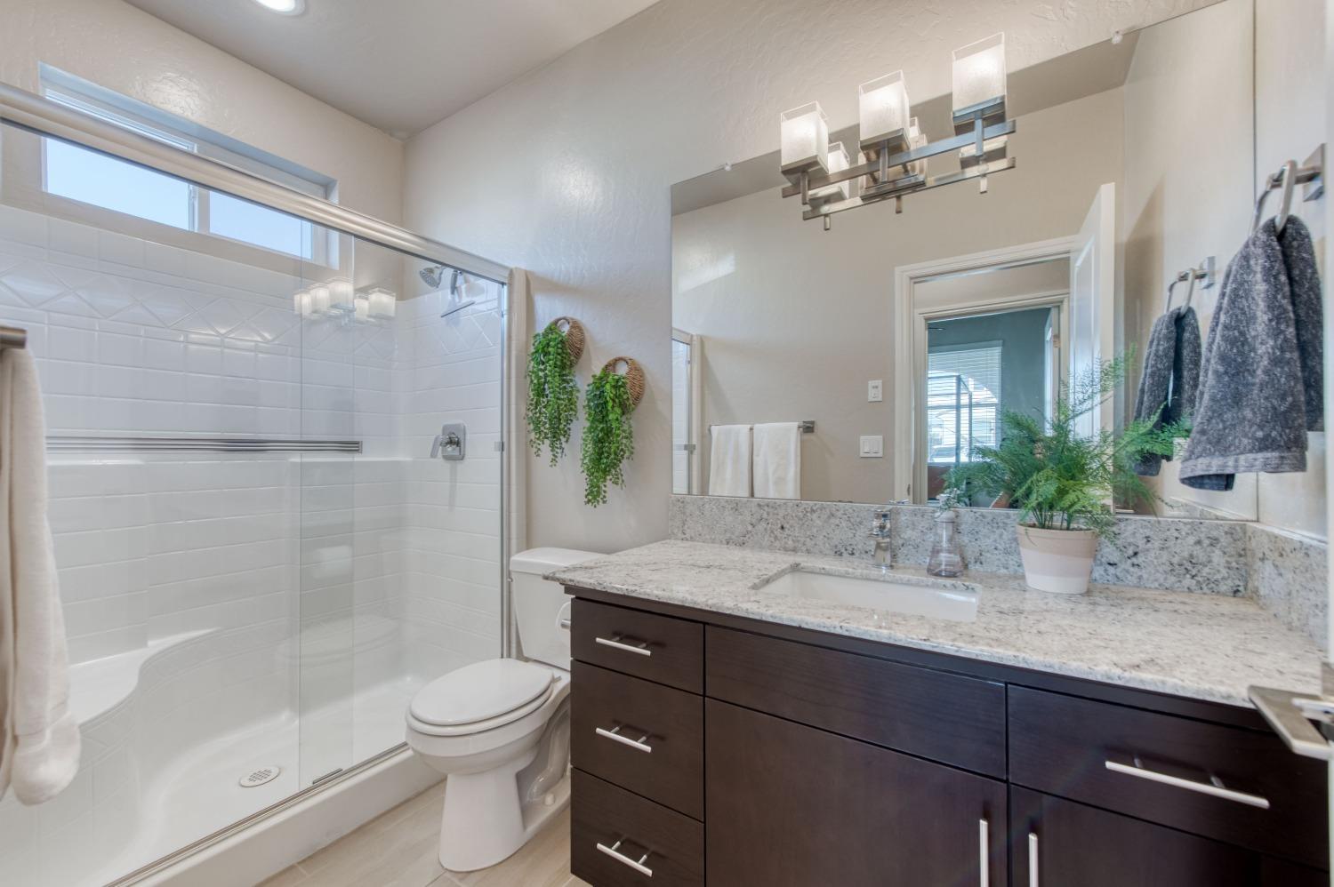 4136 Mecca Avenue Clovis, CA 93619 - Photo 22 of 44 a bathroom with a granite countertop sink a toilet and shower