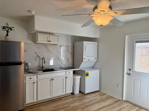 a kitchen with stainless steel appliances a refrigerator a sink and white cabinets