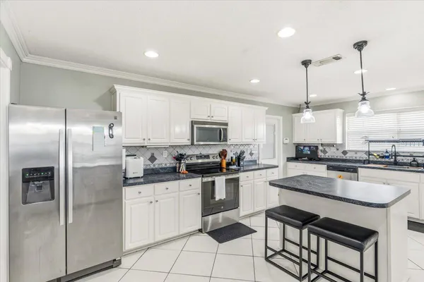 a kitchen with stainless steel appliances granite countertop a sink a stove a refrigerator and island with wooden floor