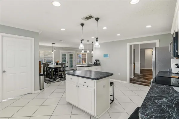 a dining hall with granite countertop a sink and white cabinets
