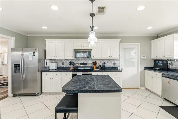 a kitchen with kitchen island granite countertop a stove a sink a refrigerator a counter top space cabinets and a window