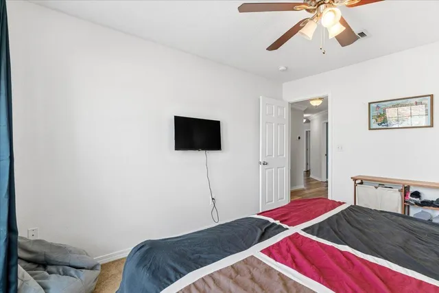 a bedroom with a bed and a flat tv screen on the dresser