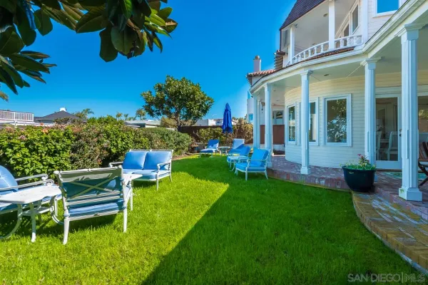 a view of a house with a yard potted plants and a bench